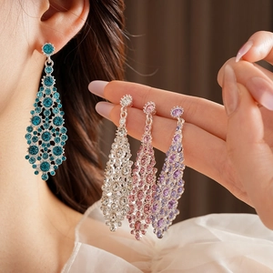 Primer plano de pendientes largos de diamantes en azul, rosa, violeta y plata elegante