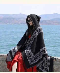 Detailed side view of ethnic hooded shawl with heart pattern in a scenic outdoor setting.