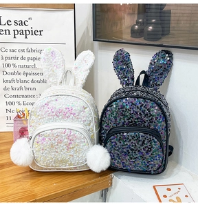 Detail of sequin backpacks in black and white with cute rabbit ears and fluffy pom poms