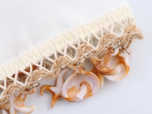 Detailed close-up of beach dress trim featuring seashells, starfish and hemp rope detail