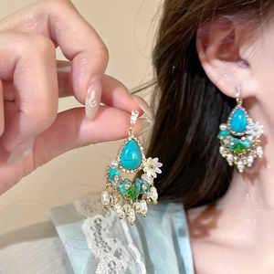 Detailed view of bohemian turquoise drop earrings with floral accents and pearl tassels