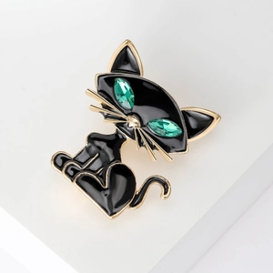 Close-up of black enamel cat brooch with gold edges and green crystal eyes