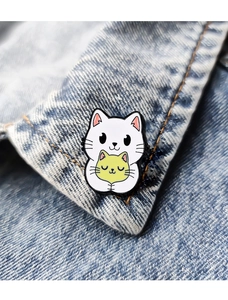 Detailed close-up of a white and yellow enamel cat pin on a denim jacket collar