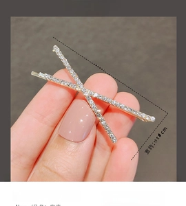 Detailaufnahme einer minimalistischen goldenen Haarklammer in X-Form mit Strasssteinen