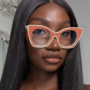 Detail of oversized cat-eye glasses with bold orange and cream two-tone contrast frame