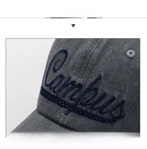 Detailed close-up of blue 3D embroidered lettering on a grey washed denim baseball cap