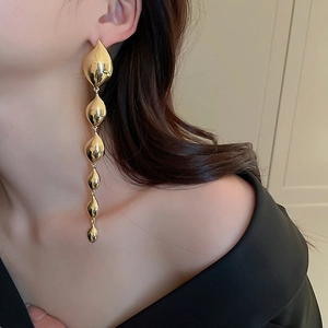 Detailed view of long gold multi-tier leaf drop earrings worn by a model