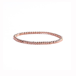 Close-up of polished rose gold beaded elastic bracelet showing metallic shine