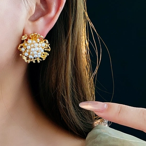 Primo piano di orecchini vintage a fiore con perle e oro indossati da una modella