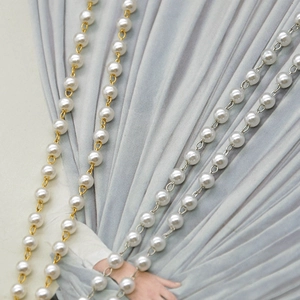 Detail of white faux pearl beaded chain with gold and silver links on grey fabric