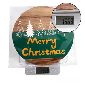 Insegna natalizia in legno su bilancia digitale che mostra il peso di 156,9g circa