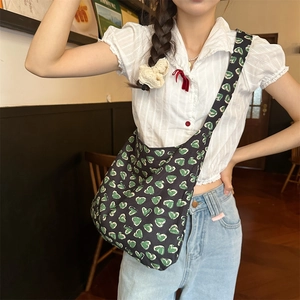 Detail of floral canvas crossbody bag with green heart pattern on black background
