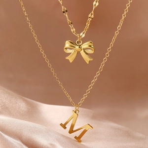 Double-layer gold stainless steel bow necklace with initial M on champagne silk