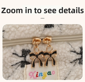 Close-up of white fleece bag showing dual gold zippers and elegant bow charms