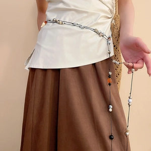Detail of vintage ethnic waist chain with amber resin beads and metal accents on model