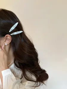 Detail of light gray puppy hair clips worn on wavy hair with pearl jewelry accessories