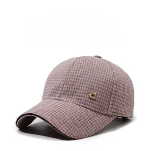 Detail of pink and grey houndstooth baseball cap with golden metal accent and sturdy brim