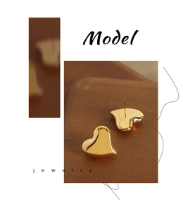 Macro detail of polished heart-shaped gold stud earrings on minimalist modern background