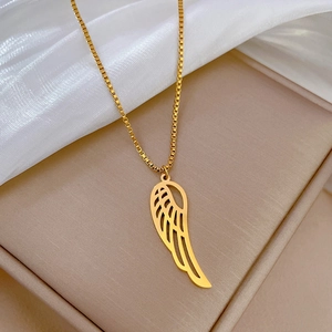 Detailed view of a gold hollow wing pendant necklace on a beige jewelry box with silk