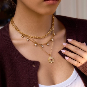 Dettaglio di tre collane a strati placcate oro 18K con ciondoli a cuore indossate da modella