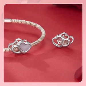 Macro shot of silver S925 heart charm with lavender center on a mesh texture bracelet