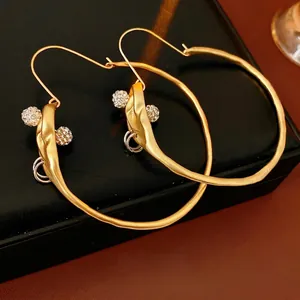 Chic twisted gold hoop earrings with sparkling rhinestone ball accents on premium leather