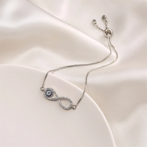 Detail of infinity charm bracelet with blue evil eye and sparkling zircon stones