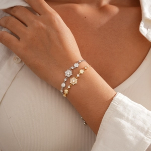 Close-up of gold and silver snowflake charm bracelets with sparkling cubic zirconia stones