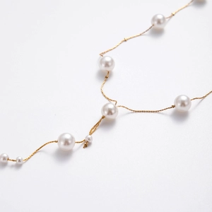 Elegant gold pearl body chain necklace with y-shaped design on a white background