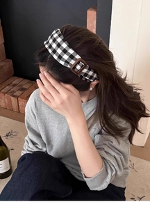 Gros plan d'un serre-tête vintage à damier noir et blanc avec boucle en cuir marron