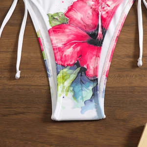 Detailed view of floral print bikini bottoms with side ties on a wooden surface