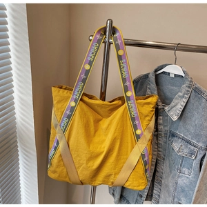 Gros plan d'un cabas en nylon jaune avec larges anses à logo et texture de tissu durable