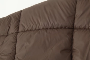 Gros plan sur un tissu matelassé marron avec coutures détaillées et fini brillant