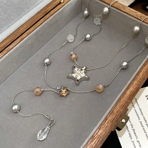 Detail of double-layer necklace with star charms, pearls, and a crystal teardrop pendant