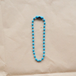 Detailed view of a 2.4mm blue metal beaded chain with secure connector on paper background