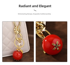 Detail of red apple charm with gold metal clasp shown on a white quilted handbag