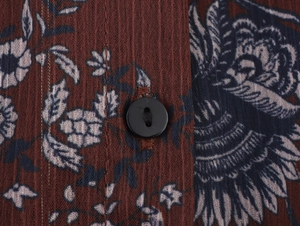Macro detail of red floral chiffon fabric texture and a black button on the dress