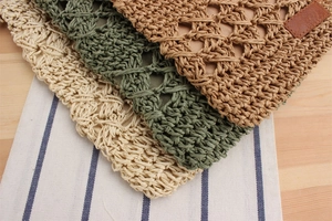 Close-up of stacked hollow woven paper rope clutch bags in khaki, green, and beige