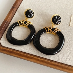 Détail de boucles d'oreilles vintage avec anneaux en résine noire et maillons dorés