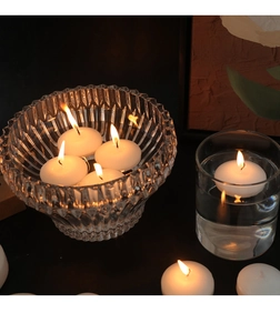 Primer plano de velas flotantes blancas ardiendo en cuencos de vidrio luz cálida