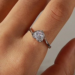 Close-up of a silver heart-shaped ring featuring a sparkling cubic zirconia stone on a finger