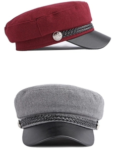 Close-up of wool baker boy hats in burgundy and grey with woven bands and metal buttons
