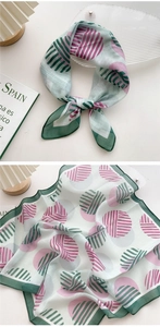 Detail of a lightweight white scarf with green borders and pink circular abstract patterns