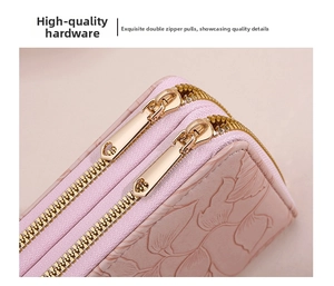 Close-up of pink leather wallet with embossed floral patterns and gold heart-shaped zippers