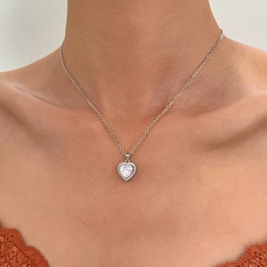 Gros plan d'un collier cœur minimaliste en argent avec zircon porté par un modèle