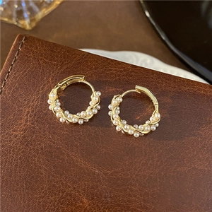 Detailed close-up of S925 silver needle pearl hoop earrings on brown leather surface