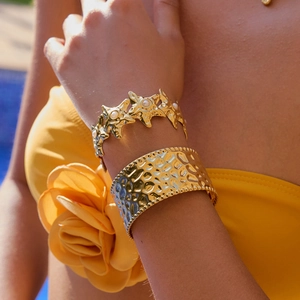 Close-up of 18k gold plated hammered cuff and starfish pearl bracelet on woman's wrist