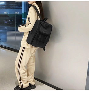 Detailed view of a black nylon backpack featuring flap closure and buckle strap design