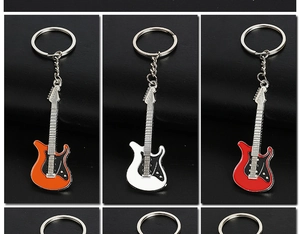 Detailed view of guitar-shaped metal keychains in orange, white, and red lacquer finish