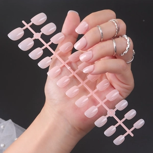Short square-oval glossy press-on nails in soft peach pink finish on a black background